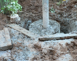 Mud around the hole containing the Sonotube filled with cement, and the pole set into it.