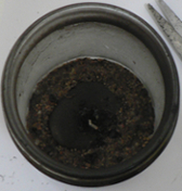 A different candle jar showing a well placed stone with the candle wax burned to nothing, leaving the wick tab